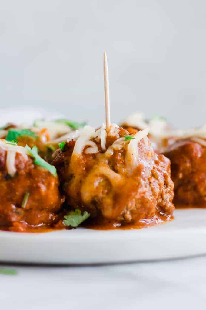 Tex Mex Chorizo Enchilada Meatballs（墨西哥辣香肠肉丸），装在带牙签的盘子里。